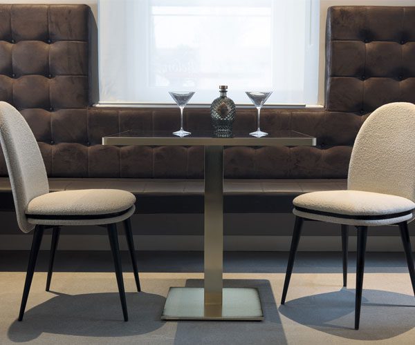 A table with two chairs and a vase on it