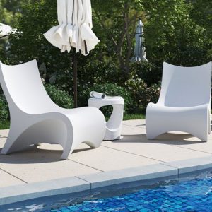 Two white lounge chairs next to a pool.