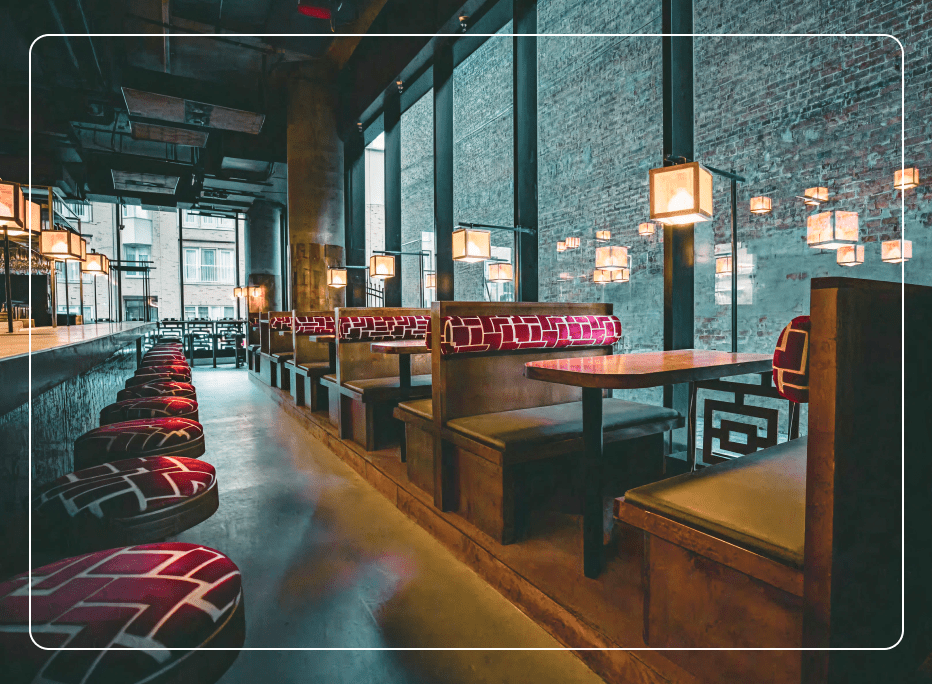 Modern restaurant interior featuring custom upholstered booths, warm ambient lighting, and large windows, illustrating how thoughtfully designed booth seating enhances comfort, flow, and dining experience.