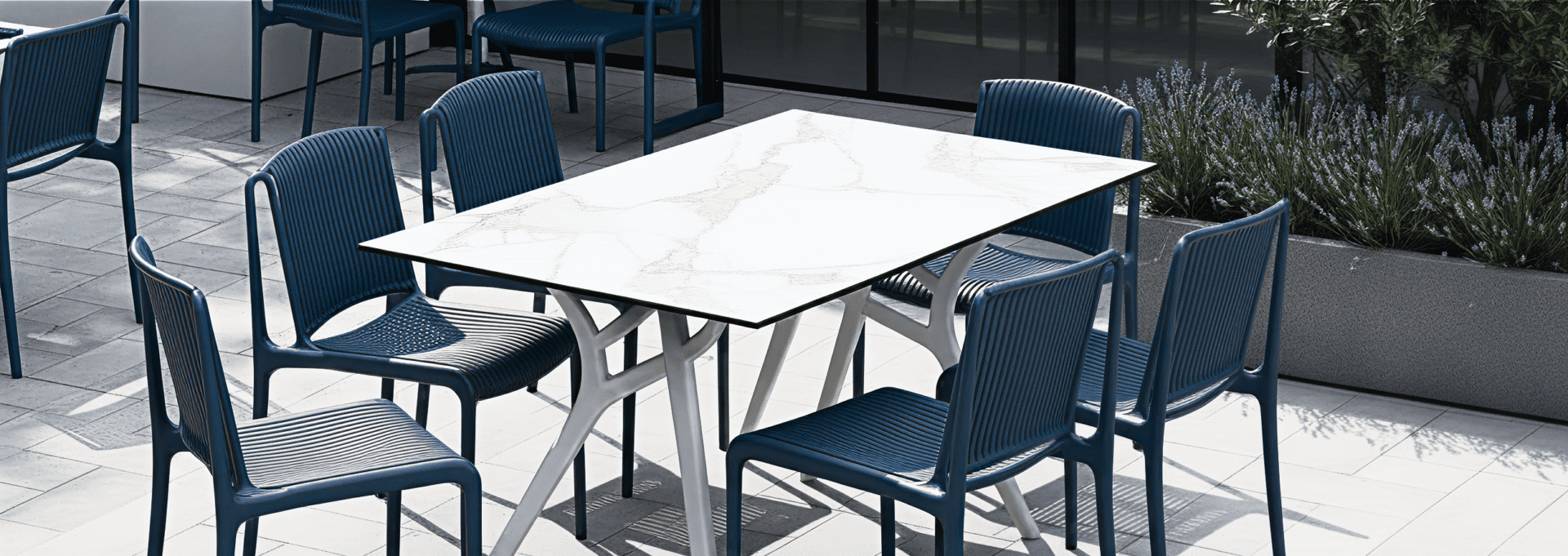 Modern outdoor seating set with blue commercial chairs and marble-look table for restaurant and hospitality patios